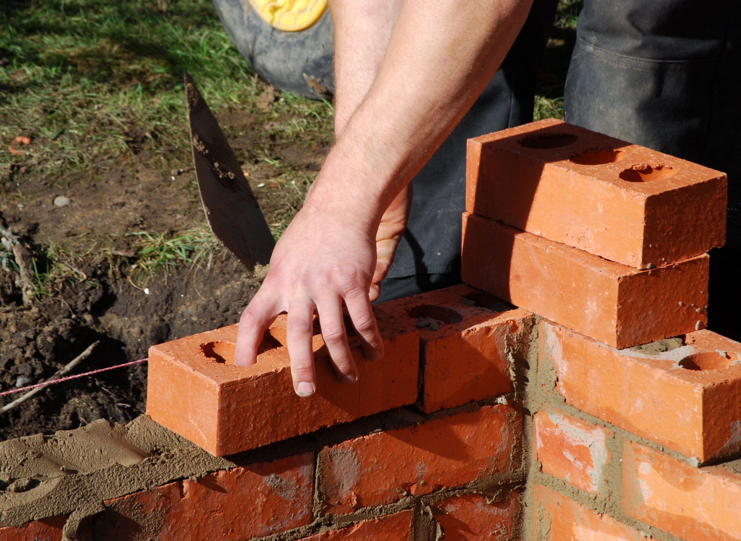 Construction worker laying bricks wall of building